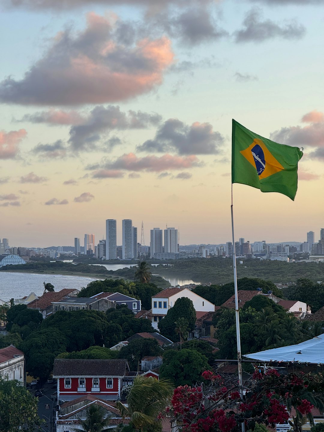 A Brazilian flag waves over a city with modern skyscrapers.